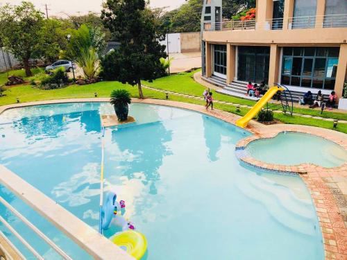 una gran piscina con un tobogán en un edificio en T3c Gardens, en Lusaka