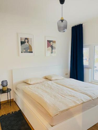 ein weißes Schlafzimmer mit einem großen Bett mit einem blauen Vorhang in der Unterkunft Zentrale Wohnung mit Blick auf Burg Altpernstein in Micheldorf in Oberösterreich