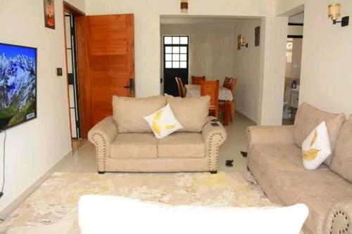 Amalia apartments syokimau near JKIA في نيروبي: غرفة معيشة مع كنبتين وطاولة