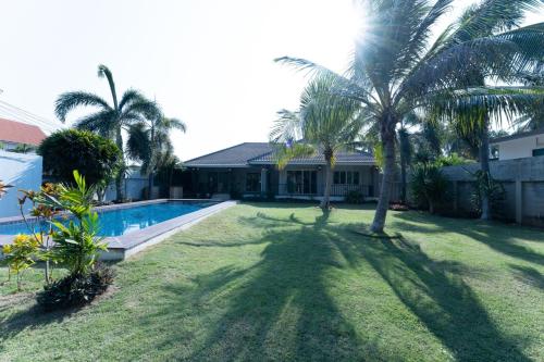 un patio con palmeras y una piscina en Cannastay, en Baanphakrimlay 