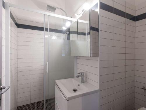 une salle de bain blanche avec un lavabo et une douche dans l'établissement Studio cosy rénové au centre de Cauterets, idéal pour 4, équipé et confortable - FR-1-401-283, à Cauterets