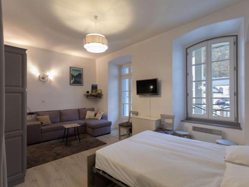 une chambre avec un grand lit et un canapé dans l'établissement Studio cosy rénové au centre de Cauterets, idéal pour 4, équipé et confortable - FR-1-401-283, à Cauterets