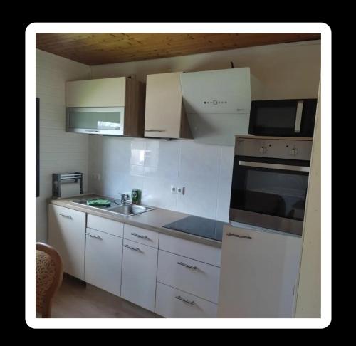 a small kitchen with white cabinets and a sink at Landhaus Westrich in Walldürn