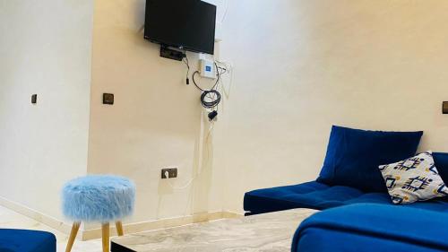 a living room with a blue couch and a tv at résidence nour 7 in Marrakech