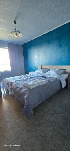 een slaapkamer met een groot bed met een blauwe muur bij Blue Appartement in Sint-Niklaas