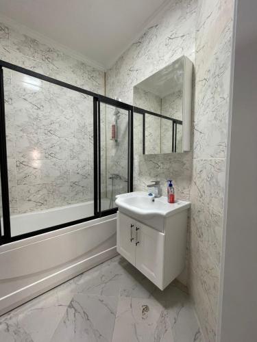 uma casa de banho branca com um lavatório e um espelho em ЖК Кокжайлау em Shymkent