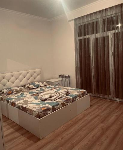 um quarto com uma cama num quarto com uma janela em ЖК Кокжайлау em Shymkent