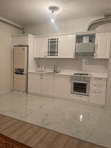 uma cozinha branca com armários brancos e um frigorífico em ЖК Кокжайлау em Shymkent