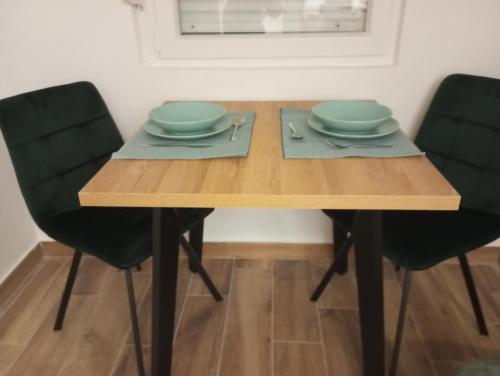 a wooden table with two chairs and two plates on it at Apartmani Marina in Rab