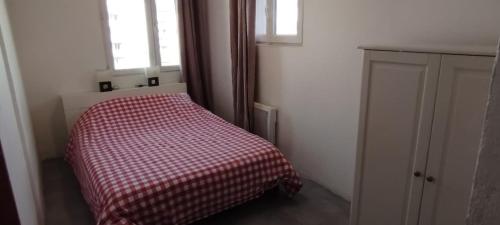 - une petite chambre avec un lit et une couverture en damier dans l'établissement Appartement lumineux, à Montreuil