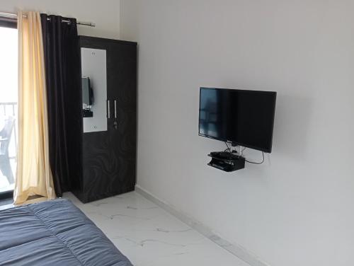 a bedroom with a flat screen tv on the wall at Western Valley Cottages , Panchagani in Panchgani