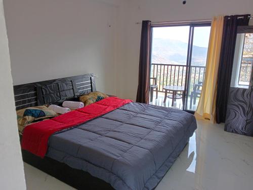 a bedroom with a bed and a balcony with a view at Western Valley Cottages , Panchagani in Panchgani