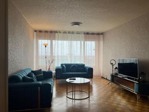 een woonkamer met een bank, een tafel en een tv bij Blue Appartement in Sint-Niklaas