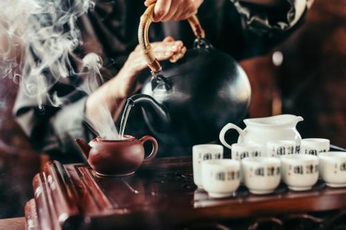 a person brewing tea in a tea pot next to cups at Hotel Hochschober in Turracher Hohe