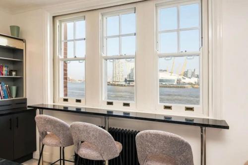 倫敦的住宿－3 x Bedroom Riverside Flat with Beach，客房设有三扇窗户和一张桌子及椅子。
