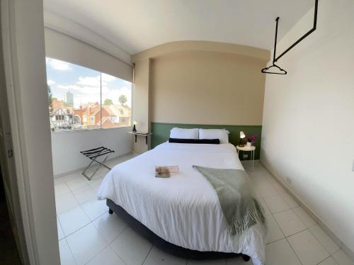 ein Schlafzimmer mit einem großen Bett und einem großen Fenster in der Unterkunft Nomadia Hostel Boutique in Bogotá