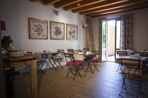 Un comedor con mesas y sillas y una ventana. en La Corte Di Anna Agriturismo, en San Giovanni Lupatoto