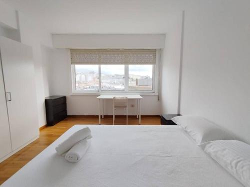 ein weißes Schlafzimmer mit einem weißen Bett und einem Tisch in der Unterkunft VibesCoruña- Marchesi F9 in A Coruña