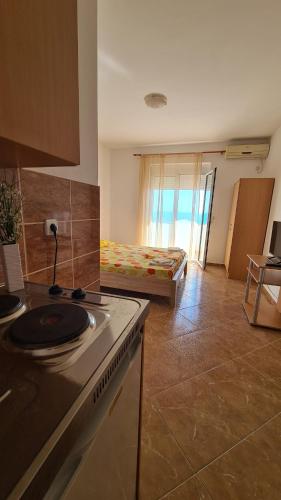 a kitchen with a stove and a room with a bed at Apartments Mare in Ulcinj