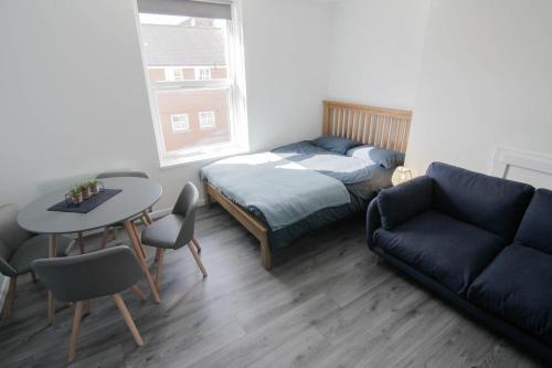 a living room with a couch and a table and a bed at Beautiful 1 Bedroom Central Flat in Leamington Spa