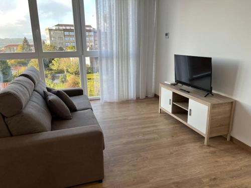 ein Wohnzimmer mit einem Sofa und einem Flachbild-TV in der Unterkunft Apartamento céntrico con vistas in Santiago de Compostela