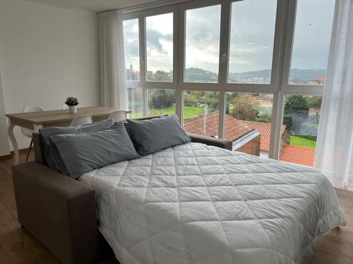 ein Bett in einem Schlafzimmer mit einem großen Fenster in der Unterkunft Apartamento céntrico con vistas in Santiago de Compostela