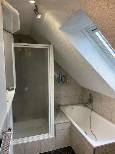 La salle de bains mansardée est pourvue d'une douche et d'une baignoire. dans l'établissement Haus Dambacher - Arbeiter-Monteurzimmer, à Nürtingen