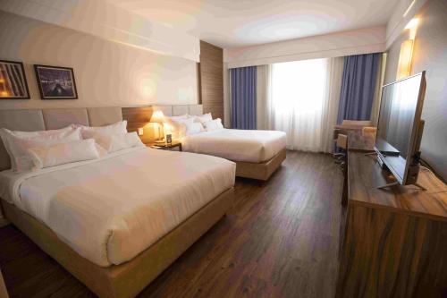 a hotel room with two beds and a flat screen tv at Vidam Hotel Aracaju - Transamerica Collection in Aracaju