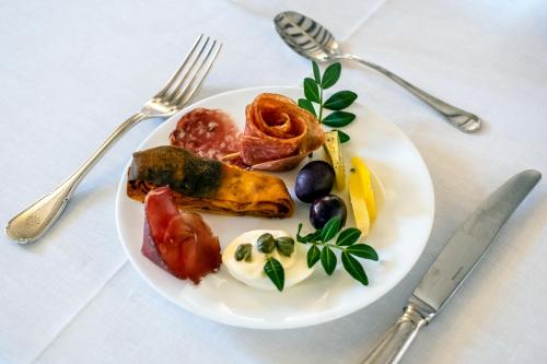 un piatto bianco con cibo su un tavolo con argenteria di Eremo Della Giubiliana a Ragusa