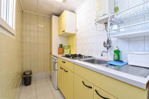 uma pequena cozinha com um lavatório e um fogão em Apartments Vlasta 1410 em Premantura