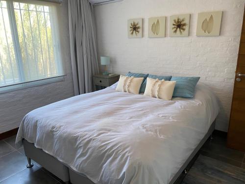 Un dormitorio con una gran cama blanca con dos almohadas. en IPB La Juanita, en José Ignacio