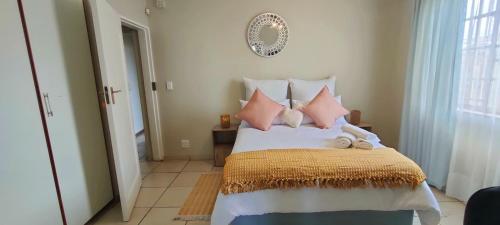 Nkulies Nest في سنتوريون: غرفة نوم مع سرير مع وسائد وردية وبيضاء