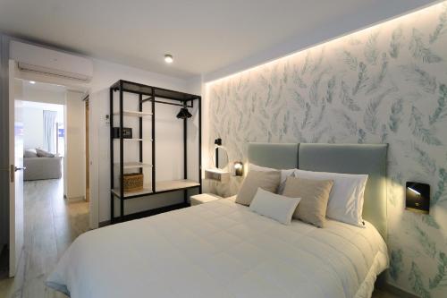 a bedroom with a white bed with a floral wallpaper at Suite apartment mar menuda in Tossa de Mar
