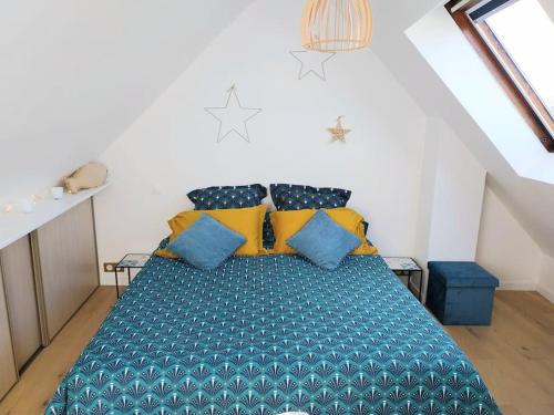 une chambre avec un lit avec des oreillers bleus et jaunes dans l'établissement Appartement Cosy Ploumanac'h classé 2 étoiles, à Perros-Guirec