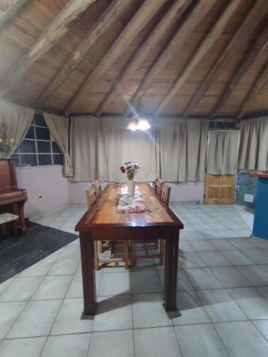 einen Holztisch mit Stühlen und eine Vase mit Blumen darauf in der Unterkunft LaFinca in Las Heras