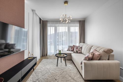 een woonkamer met een bank en een tafel bij Krynica Apartamenty - Apartament z sypiąlnią i parkingiem Cicha 18 in Krynica Zdrój