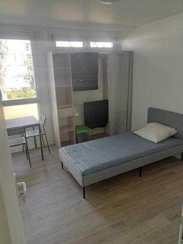 une chambre avec un lit, un bureau et une télévision dans l'établissement Appt Sarcelles, à Sarcelles