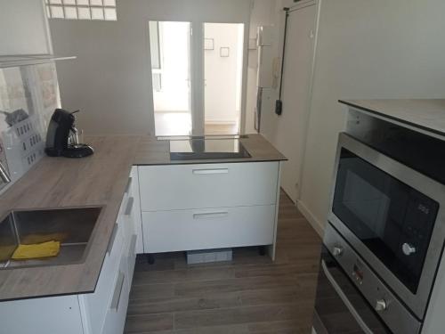 une cuisine avec des armoires blanches et un comptoir dans l'établissement Appt Sarcelles, à Sarcelles