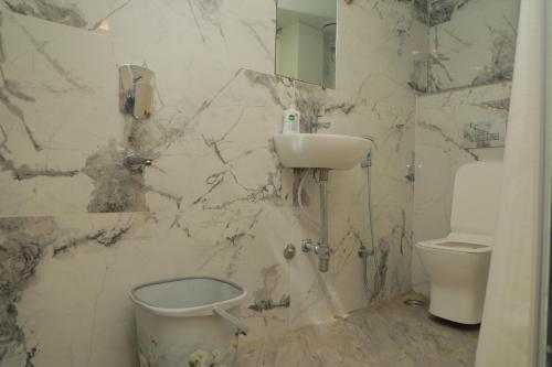 baño de mármol con lavabo y aseo en De Classico Hotel, en Varanasi