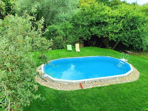 ein Pool in einem Garten mit zwei Stühlen im Gras in der Unterkunft Somogy Kertje Üdülőfalu és Étterem in Bonnya