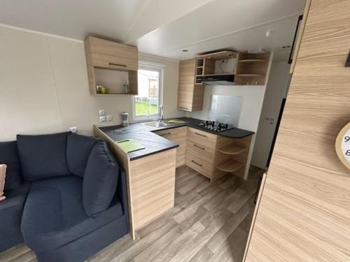 - une petite cuisine avec un canapé bleu dans une chambre dans l'établissement Mobile- Home AMIRA, à Valras-Plage