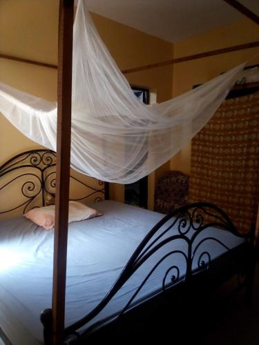 a bedroom with a canopy bed with a mosquito net at Maison Manour, suite Maison Manour, chambre avec salle de bain privée in Mbour