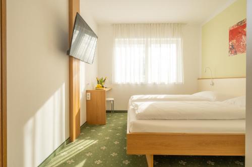 a bedroom with two beds and a flat screen tv at Hotel B3 in Mauthausen