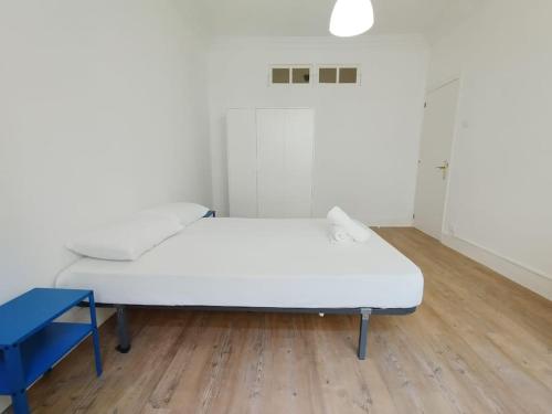 ein weißes Bett in einem Zimmer mit einem blauen Stuhl in der Unterkunft VibesCoruña- Ferrocarril 2 in A Coruña