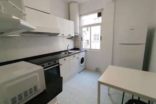 eine weiße Küche mit einer Spüle und einer Mikrowelle in der Unterkunft VibesCoruña- Ferrocarril 2 in A Coruña