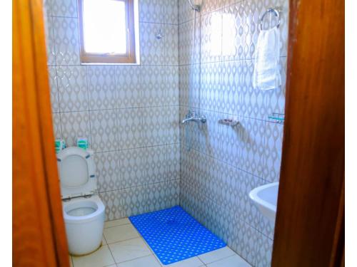 a bathroom with a toilet and a shower and a sink at Macchiato Suites in Kigali