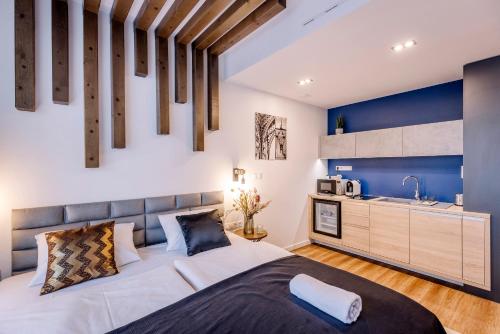 a bedroom with a large bed and a kitchen at Amade Apartments in Győr
