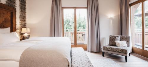 a bedroom with a bed and a chair and a window at Hotel Oberforsthof in Sankt Johann im Pongau