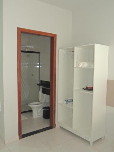 a white bathroom with a toilet and a mirror at Porto Residence in Vitória da Conquista