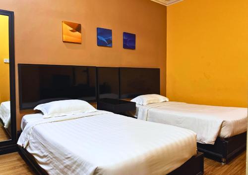 two beds in a room with yellow walls at Penview Hotel in Kuching